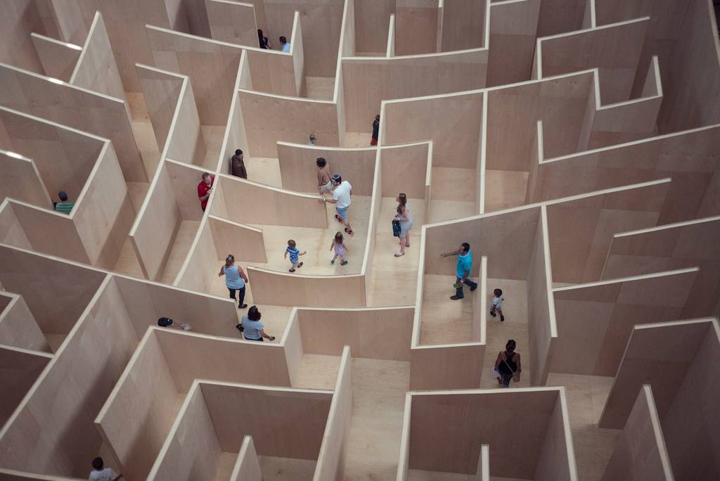 People navigating a wooden maze structure.